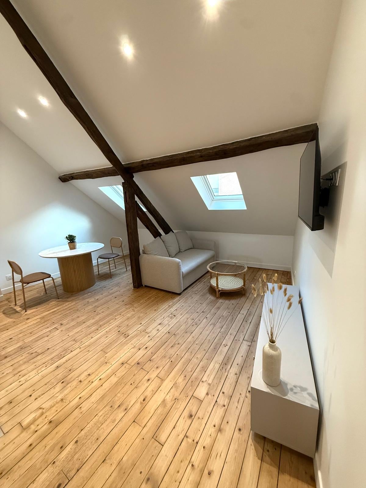 Le charme des poutres : Volumes sous toiture, parquet et matières minérales.